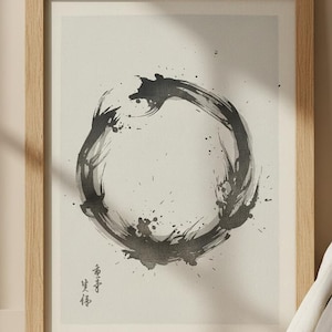 以下が含まれることがあります： 禅仏教の象徴である黒インクの円が描かれた額入りのプリント。アートワークは明るい木製のフレームに入っており、白い枕とベージュの寝具のあるベッドの上に掛けられています。プリントには日本語の文字が含まれています。