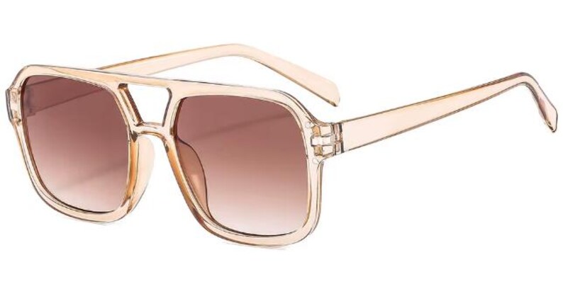 May include: Sunglasses with a beige frame and brown gradient lenses. The square-shaped sunglasses feature a double bridge and a light-coloured frame. The lenses transition from a darker brown at the top to a lighter brown at the bottom.