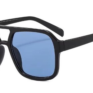 May include: Black square sunglasses with blue lenses. The sunglasses feature a double bridge and thick arms. The lenses are a solid blue, and the frames have a matte black finish. A stylish accessory for eye protection.