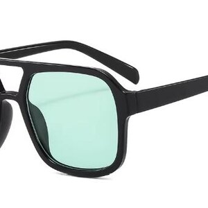 May include: Black square-framed sunglasses with light green lenses. The sunglasses have a double bridge and thick temples. The lenses are a solid, opaque colour. The overall style is modern and bold.