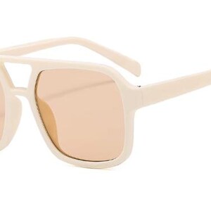 May include: Cream-coloured sunglasses with a square frame and peach-tinted lenses. The sunglasses have a double bridge and thick temples. The overall design is retro-inspired, offering a bold and stylish look.