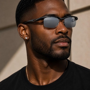 May include: Semi-rimless sunglasses featuring a sleek black frame and reflective silver lenses. The design includes a thin bridge and contoured temples, providing a streamlined look with a polished finish that offers clear visibility and sun protection.