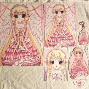 May include: A collection of anime-style merchandise featuring a blonde character with large dark eyes and white wings, wearing a pink ruffled dress. The set includes two rectangular art prints, a heart-shaped keychain, and an acrylic standee.
