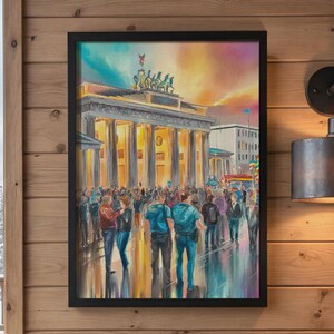 Op de afbeelding: Een ingelijste kunstdruk van de Brandenburger Tor in Berlijn bij schemering. De afbeelding toont een menigte op de voorgrond, de verlichte zuilen van het monument en een levendige lucht in oranje en blauwe tinten op de achtergrond.