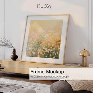 May include: A framed art print featuring a floral field in soft yellow, green, and pink tones. The artwork is displayed in a light wood frame, leaning against a white wall. The text "Frame Mockup" is visible.