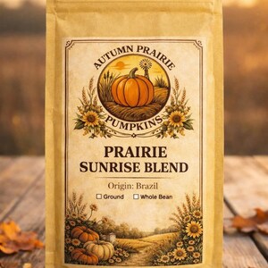Könnte beinhalten: Ein beigefarbener Kaffeebeutel mit dem Text "Autumn Prairie Pumpkins" und "Prairie Sunrise Blend". Das Etikett zeigt eine Kürbisillustration mit Sonnenblumen. Herkunft: Brasilien, gemahlen oder ganze Bohne.