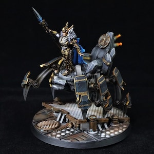 May include: A detailed miniature figure of a warrior riding a mechanical spider-like vehicle. The warrior is clad in gold and blue armor, holding a weapon. The vehicle is gray and black, with intricate mechanical details. The base is round and metallic.