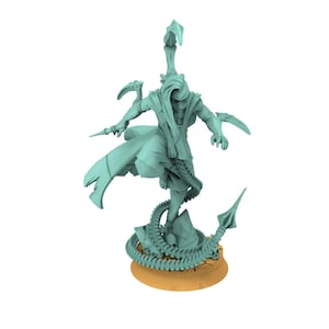 Puede incluir: Figura de color verde azulado claro de un guerrero con una capa fluida, sosteniendo una daga y de pie sobre una base rocosa. Una cola de escorpión se enrolla alrededor de la base. La figura está sobre una base circular de color canela.