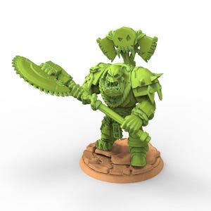 Puede incluir: Figura en miniatura verde de un guerrero de fantasía, empuñando un arma grande con forma de sierra. La figura está detallada con armadura y un emblema con forma de calavera. Se encuentra sobre una base marrón texturizada, sobre un fondo blanco.
