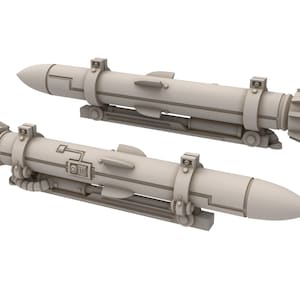 May include: Two light gray, cylindrical objects with pointed and finned ends, mounted on a rectangular base. The objects have detailed surface features, including bands, panels, and what appears to be a control panel.