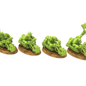 Puede incluir: Cuatro figuras en miniatura verdes de personajes de fantasía montados en motocicletas. Cada figura está montada en una motocicleta con una rueda delantera puntiaguda y una base marrón. Las figuras sostienen armas, incluyendo hachas y cuchillas.