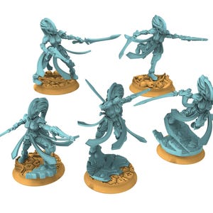 Op de afbeelding: Een verzameling lichtblauwe miniatuurfiguren van een vrouwelijke krijger, elk met een zwaard. De figuren staan op bruin-gele bases, sommige met schedels of geometrische patronen. De krijger staat in een dynamische pose.