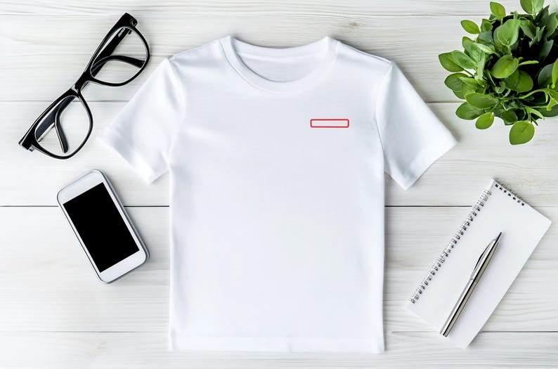 May include: A plain white short-sleeved t-shirt featuring a small, rectangular red outline graphic positioned on the upper left chest area. The garment has a classic crew neckline and a simple, clean design suitable for casual wear.