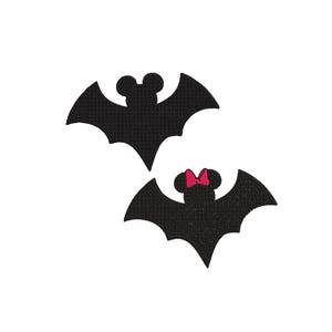 May include: Two black embroidered patches shaped like bats with rounded ears. One bat features a small, bright pink bow centred between its ears. The embroidery has a textured, stitched appearance with clean edges and a solid black colour fill.