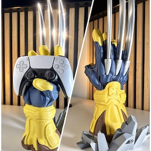 May include: A yellow and blue gauntlet-style stand featuring three long silver metallic claws extending upward. The stand is designed to hold a white and black video game controller, with a base shaped like jagged gray rock fragments.
