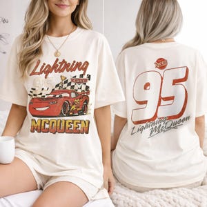 Puede incluir: Camiseta color crema con un gr&aacute;fico desgastado de Rayo McQueen de la pel&iacute;cula Cars. El dise&ntilde;o frontal incluye el texto "Lightning McQueen 95" y la parte trasera muestra un gran "95" con "Lightning McQueen" debajo.