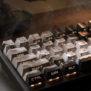 Könnte beinhalten: Eine schwarze mechanische Tastatur mit weißen und schwarzen Tastenkappen. Die Tastenkappen haben japanische Schriftzeichen und englische Buchstaben. Die Tastatur wird von einem warmen Licht beleuchtet. Zu den Tasten gehören Tab, CapsLock, Shift, Ctrl, Win und Alt.