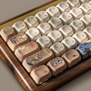 May include: A custom mechanical keyboard with a wooden frame and cream-colored keycaps. Some keycaps feature Japanese characters and illustrations of boats and landscapes in shades of brown, blue, and beige. The keyboard has a gold accent.