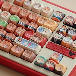 May include: A handmade wooden sign displaying the word "Welcome" in a whimsical font. The sign is painted white with a distressed finish, and features a floral design in pinks and greens. It measures approximately 30 cm wide and 15 cm high.