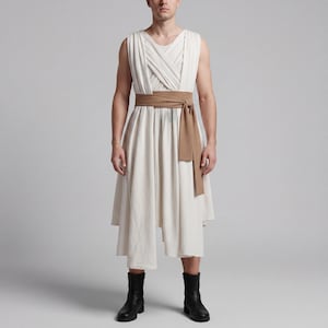 May include: A sleeveless, off-white dress with a draped bodice and a brown waist sash. The dress has an asymmetrical hemline and is paired with black ankle boots. The outfit is simple and elegant.