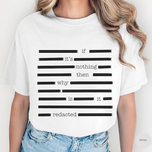 Può includere: T-shirt bianca con un design di testo nero oscurato. Il testo recita "se non è niente, allora perché è oscurato". Una t-shirt in stile casual, adatta all'uso quotidiano.