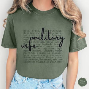 May include: An olive green t-shirt with the words "military wife" in a script font. The shirt has a list of phrases related to military life in a smaller font. The t-shirt is a comfortable, casual style.