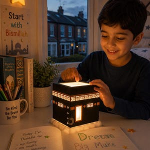 Young child enjoying a warm illuminated Kaaba night light during quiet evening reading time.