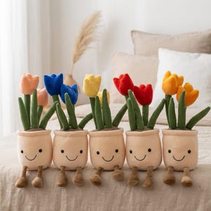 May include: A row of plush tulip flower toys in beige pots with smiling faces and small brown feet. The tulips are in various colors, including orange, blue, yellow, and red, with green stems and leaves.