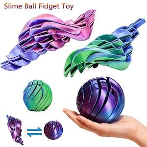 May include: A selection of Slime Ball Fidget Toys in metallic, iridescent colours. The toys are in shades of purple, blue, and green. The text "Slime Ball Fidget Toy" is at the top. One toy is held in a hand.