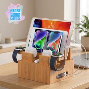 May include: A bamboo charging station with multiple slots for electronic devices. It holds a tablet, two smartphones, two smartwatches, and two sets of earbuds. The devices are charging, with visible charging indicators on the screens. The text "HEART WOOD GIFTS" is in the upper left corner.