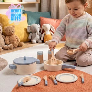 May include: Wooden toy kitchen set with a light blue and natural wood finish. The set includes a pot, pan, plates, utensils, and two small containers. The image also shows stuffed animal toys and the text "HEART WOOD GIFTS".