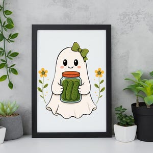 May include: A framed wall art print featuring a white ghost character with a green bow, holding a glass jar filled with green pickles. The illustration includes two yellow flowers on either side of the ghost, all set against a plain white background.