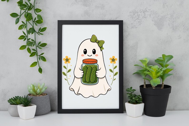 May include: A framed wall art print featuring a white ghost character with a green bow, holding a glass jar filled with green pickles. The illustration includes two yellow flowers on either side of the ghost, all set against a plain white background.