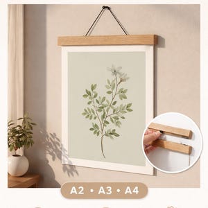 Peut inclure: Un porte-affiche magnétique en bois avec une impression botanique. L'impression présente un motif floral vert et blanc. Le texte "Magnetic Poster Hanger - WOODEN FRAME" est en haut. Disponible en tailles A2, A3 et A4.