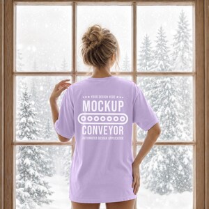 Może przedstawiać: Jasnofioletowy t-shirt z krótkim rękawem z białym napisem na plecach: YOUR DESIGN HERE MOCKUP CONVEYOR AUTOMATED DESIGN APPLICATOR oraz grafiką przedstawiającą ikonę przenośnika taśmowego między słowami MOCKUP i CONVEYOR.