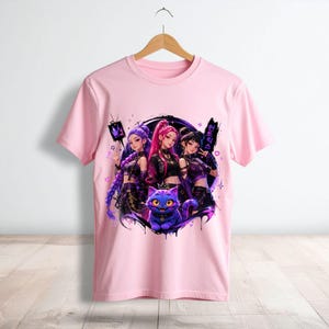 Pode incluir: Uma t-shirt de manga curta rosa claro com uma impress&atilde;o gr&aacute;fica de tr&ecirc;s personagens estilo anime e um gato roxo. O design inclui salpicos de tinta preta, pequenos cora&ccedil;&otilde;es, estrelas e caracteres de texto coreano no lado direito.