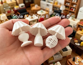 May include: Three miniature white table lamps labeled Style A, Style B, and Style C. Style A has a rounded base, Style B features a smooth tapered base, and Style C has a cage-like base. Each lamp includes a pleated, flared lampshade.