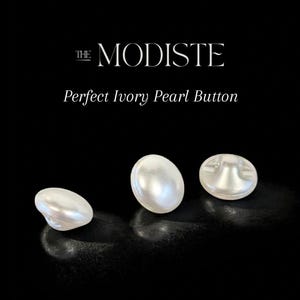 Peut inclure: Trois boutons en perle ivoire sur fond noir. Les boutons ovales présentent une finition brillante. Le texte "THE MODISTE" et "Perfect Ivory Pearl Button" sont affichés au-dessus des boutons.
