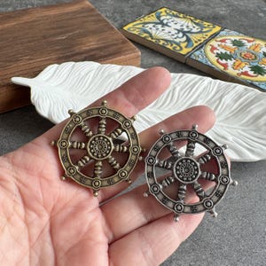 May include: A white ceramic mug with a black handle and the text "But First, Coffee" in a bold, black font. The mug is set against a blurred background, suggesting a cozy setting.