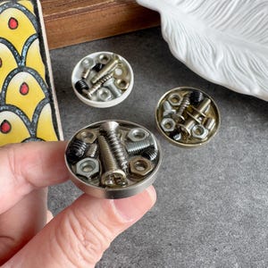 Può includere: Un set di tre tazze in ceramica con finitura opaca e macchiettata. Le tazze sono nei toni del crema, grigio chiaro e grigio scuro. Ogni tazza ha un design semplice e minimalista.