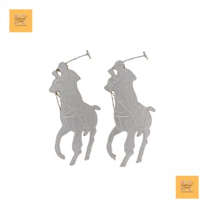 Op de afbeelding: Een paar zilverkleurige oorbellen met de silhouetten van een polospeler te paard. De oorbellen zijn gedetailleerd met getextureerde lijnen en de polospeler houdt een mallet vast. De oorbellen staan tegen een witte achtergrond.