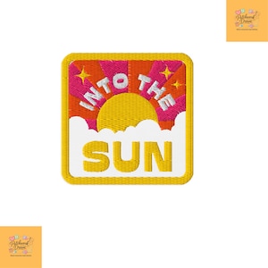 Op de afbeelding: Een vierkante geborduurde patch met een gele zon die opkomt boven witte wolken tegen een achtergrond van roze en oranje zonnestralen. De tekst INTO THE SUN is geborduurd in wit en geel, geaccentueerd door kleine gele sterren op een gele rand.