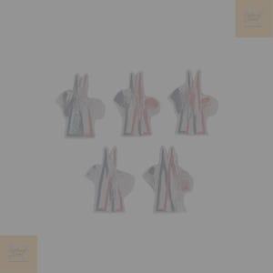 May include: Five abstract bunny-shaped patches. Each patch features a white base with black and red accents. The patches are arranged in a cluster on a grey background. The patches appear to be handmade.