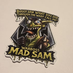 May include: A sticker featuring a green goblin with goggles, a large mouth, and a protruding tongue. The text "Buggy saw what you did through the warp, call me!" and "Warboss Mad Sam" are also on the sticker.