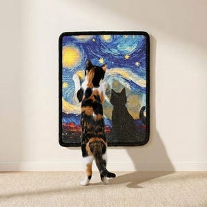 May include: A calico cat stands on its hind legs, paws touching a framed rug depicting Van Gogh's "Starry Night." A black cat silhouette is on the rug. The rug has a black border and is mounted on a white wall.