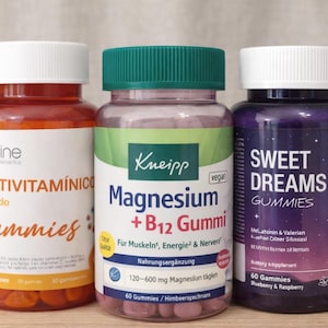 Puede incluir: Tres botellas de suplementos con tapas blancas. Las botellas contienen gomitas. Una es naranja con el texto "MULTIVITAMÍNICO", otra es rosa con el texto "Magnesium + B12 Gummi" y la última es morada con el texto "SWEET DREAMS GUMMIES".