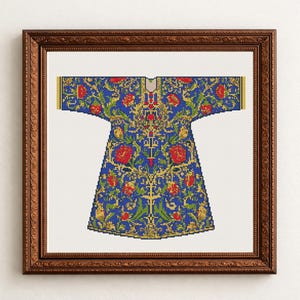 May include: A framed cross-stitch pattern of a blue garment with red floral and gold leaf accents. The artwork is displayed in a dark brown wooden frame, showcasing a detailed, ornate design. The piece is a decorative textile.