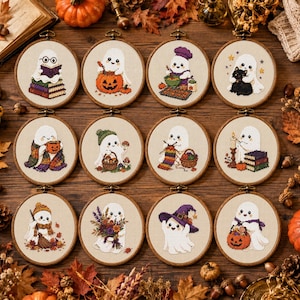 May include: Twelve circular wooden embroidery hoops containing cross-stitch designs of white ghosts. Each ghost is depicted in different activities, including reading books, holding pumpkins, cooking, knitting, and carrying flowers, all on a light fabric.