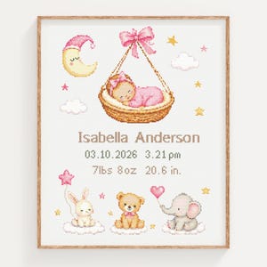 Può includere: Un ricamo a punto croce con un bebè in una cesta sospesa, una luna crescente e animali tra cui un coniglio, un orso e un elefante. Il testo riporta: Isabella Anderson, 03.10.2026, 15:21, 3402g, 52,3 cm. Con accenti rosa e gialli nel disegno.