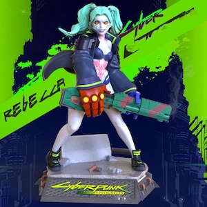 May include: A detailed figurine of a female character from Cyberpunk: Edgerunners. She has teal hair, orange eyes, and is wearing a dark blue jacket, pink and blue outfit, and black boots. She holds a green and red weapon. The base reads "Cyberpunk Edgerunners".